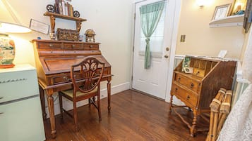 A room with a wooden desk, chair, and a dresser with drawers.