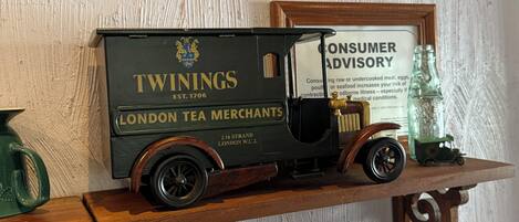 Ein Modell eines alten Tee-Lieferwagens mit der Aufschrift 'TWININGS LONDON TEA MERCHANTS', platziert auf einem Holzregal.