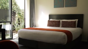 Habitación de hotel con una cama, una silla y vistas a zonas verdes.
