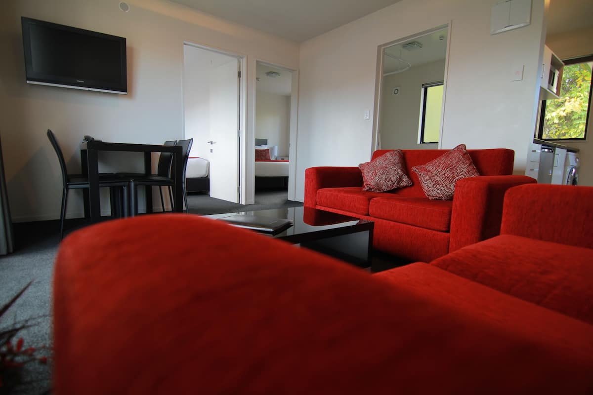 Ein modernes Wohnzimmer mit einem roten Sofa, einem schwarzen Couchtisch und einem an der Wand montierten Fernseher.