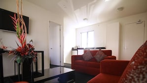 Un salón con un sofá rojo, una mesa de centro de cristal y una planta decorativa.