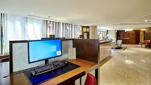 A hotel reception area with a computer desk, a red chair, and a wooden reception desk. - Hotel HD Palace (Taipei)