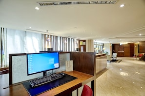 Ein Hotel-Rezeptionsbereich mit einem Computertisch, einem roten Sessel und einem Holzbüro.