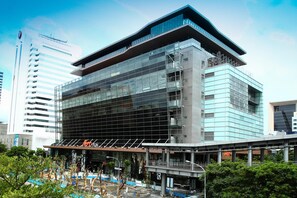 Um edifício moderno com fachada de vidro, telhado plano e área de entrada coberta.