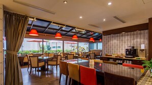 A restaurant with wooden tables and chairs, red pendant lights, and a view of greenery outside. - Hotel HD Palace (Taipei)