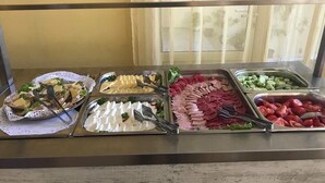 Un buffet proposant une variété de plats, notamment des salades, des viandes et des fromages.