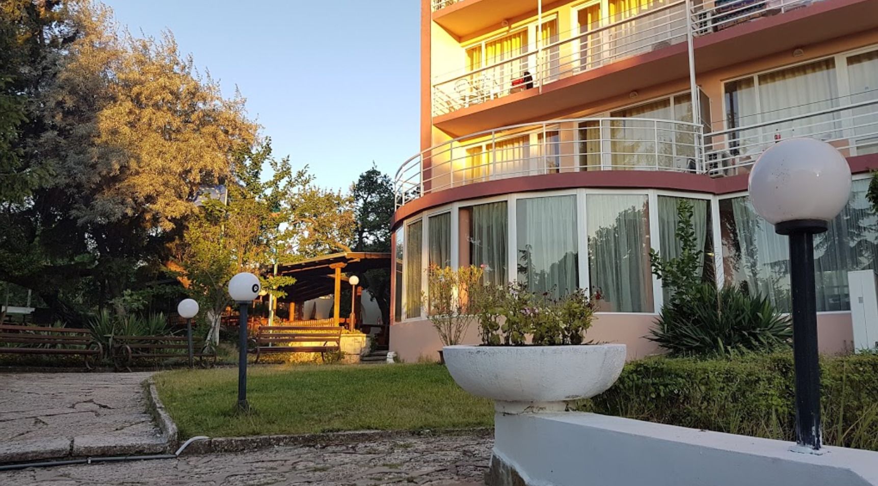 Ein mehrstöckiges Gebäude mit einer geschwungenen Fassade, großen Fenstern und einem Balkon in den oberen Etagen.