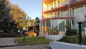 Un immeuble à plusieurs étages doté d’une façade incurvée, de grandes fenêtres et d’un balcon aux étages supérieurs.