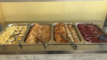 Ein Buffet mit verschiedenen Speisen, darunter Eier, Pfannkuchen und Würstchen.