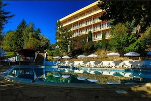 Um hotel com área de piscina, espreguiçadeiras e guarda-sóis.
