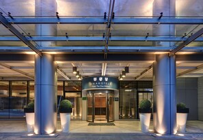 A modern hotel entrance with a revolving door, large pillars, and potted plants. - UNA Hotels The One Milano (San Donato Milanese)