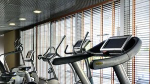 A gym with treadmills, elliptical machines, and stationary bikes. - UNA Hotels The One Milano (San Donato Milanese)