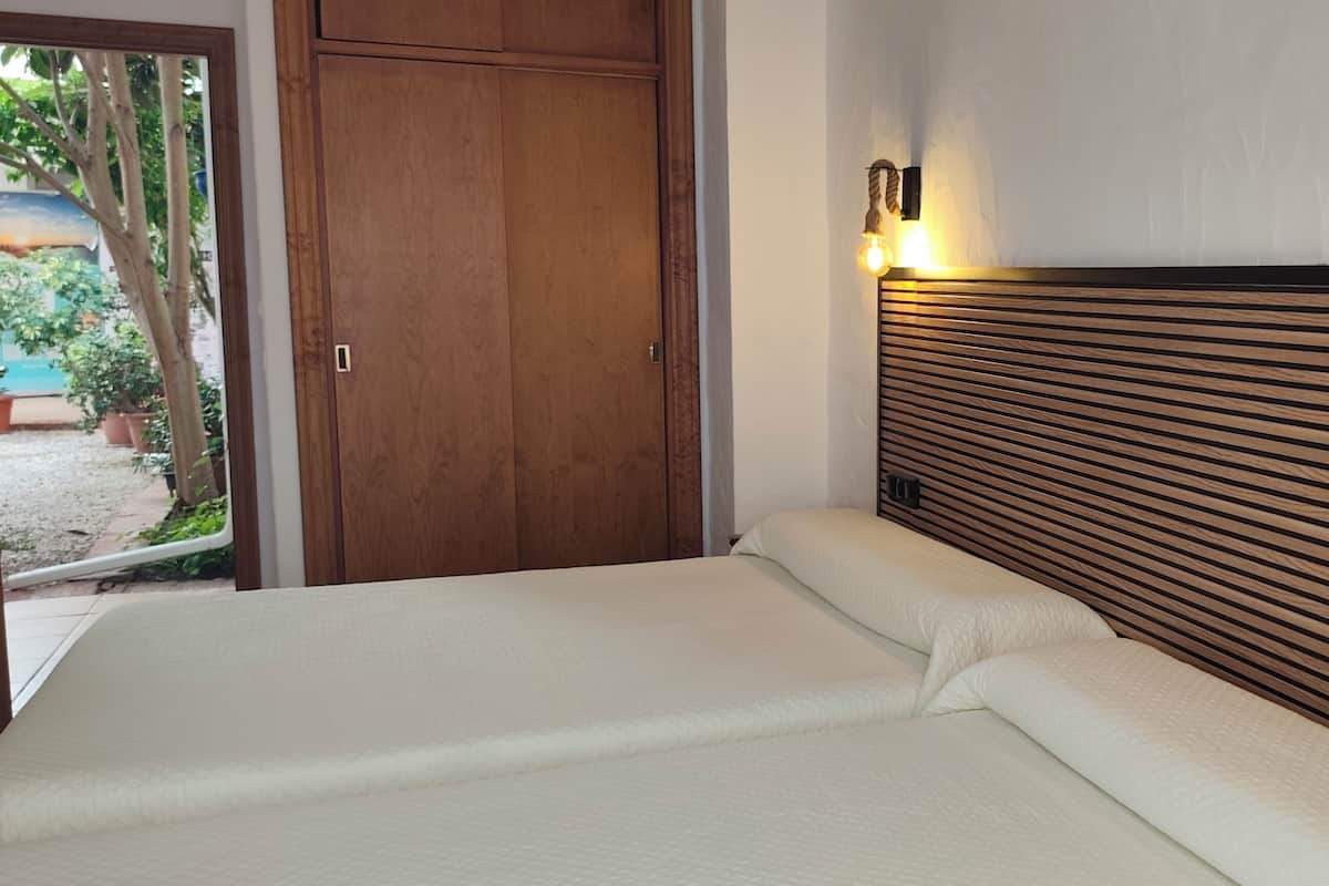 A bedroom with a wooden slat headboard, two bedside tables, and a door leading to a balcony.