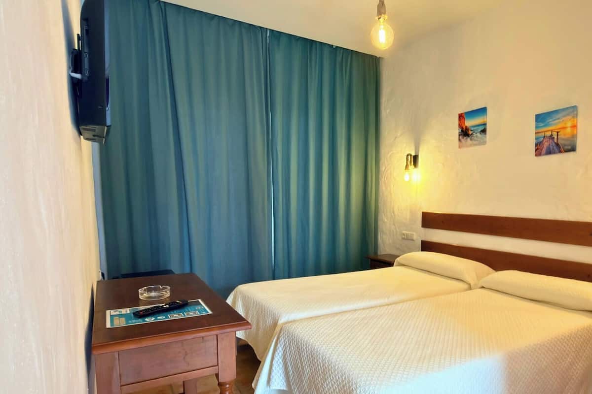 A hotel room with a bed, bedside tables, a desk, and two wall-mounted light fixtures.