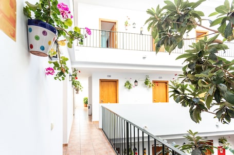 A multi-level building with balconies, potted plants, and a tiled floor.