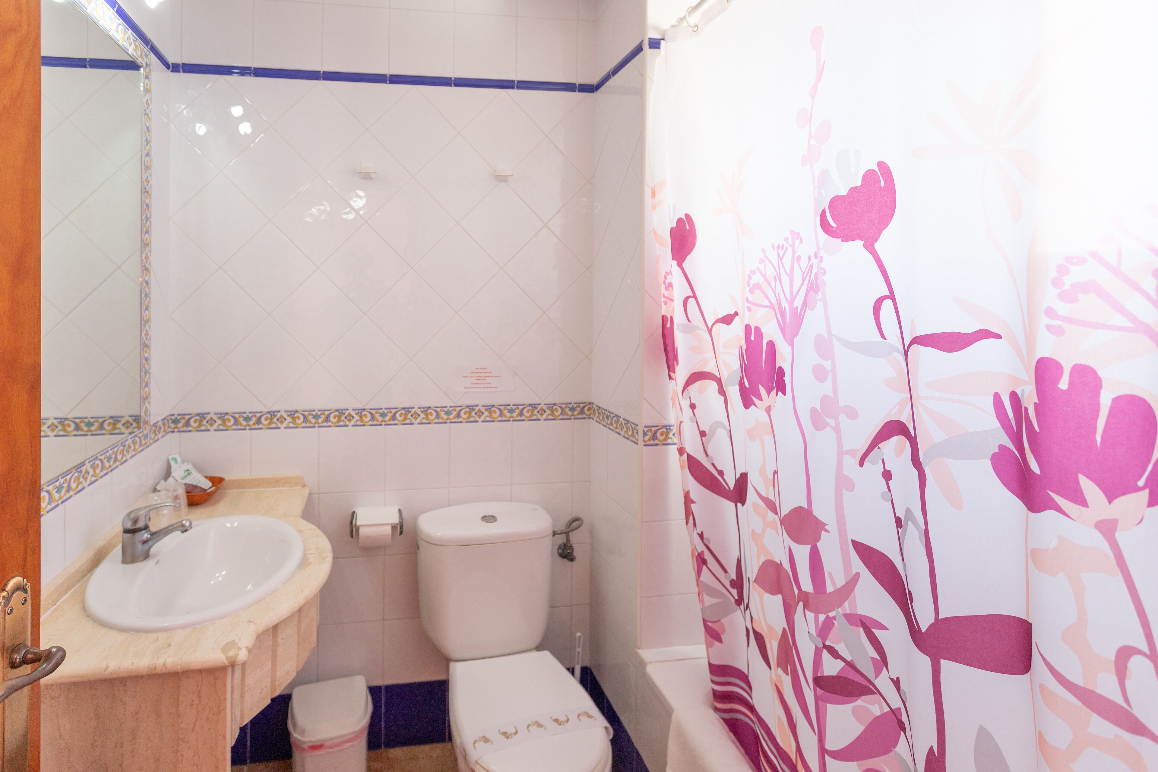 A bathroom with a sink, toilet, and shower curtain.
