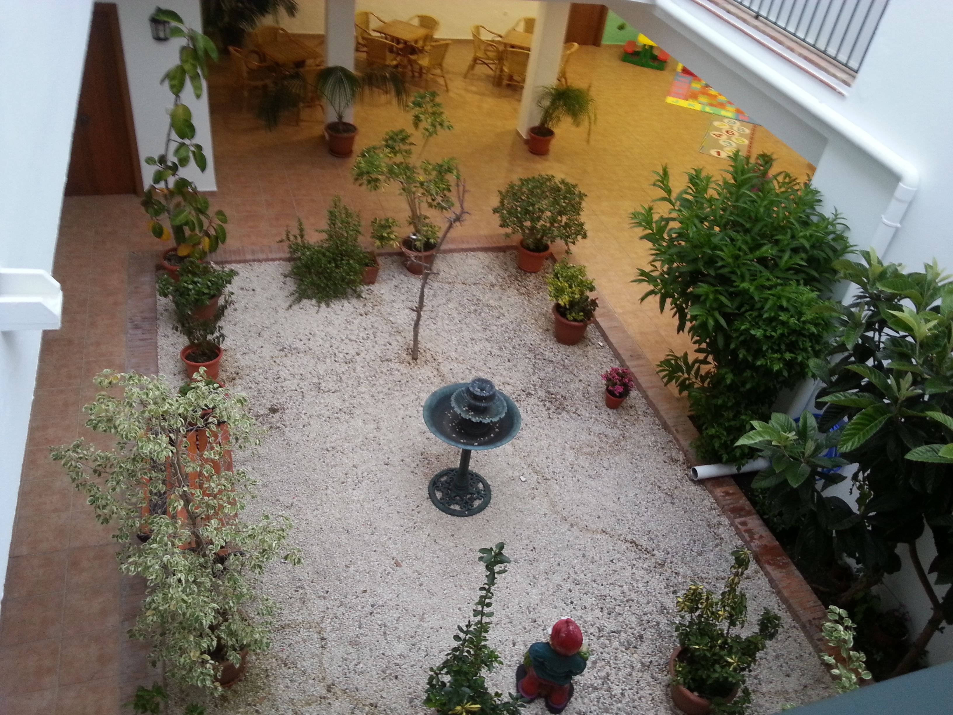 A courtyard with potted plants, a fountain, and outdoor seating.