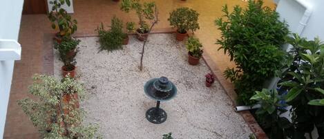 A courtyard with potted plants, a fountain, and outdoor seating.