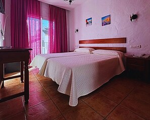 A hotel room with two beds, a wooden headboard, a desk, and a chandelier. - Hotel Oasis Atalaya (Conil de la Frontera)