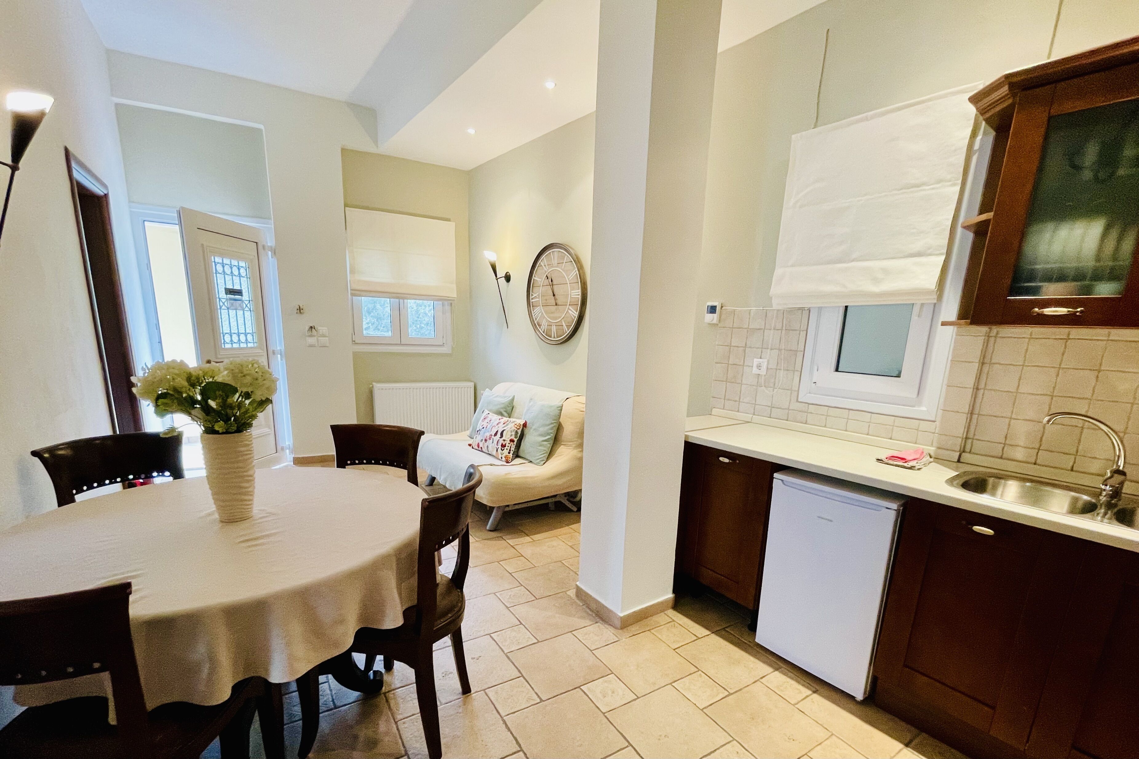 Una cucina moderna con zona pranzo, che include un tavolo rotondo, sedie, una sveglia e una lavastoviglie integrata.