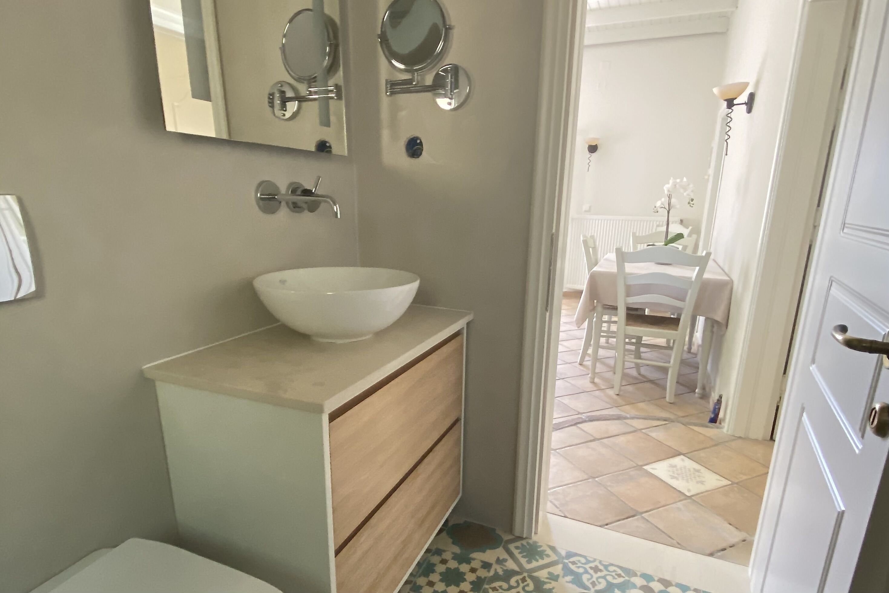 A bathroom with a white sink, wooden vanity, and two wall-mounted mirrors.