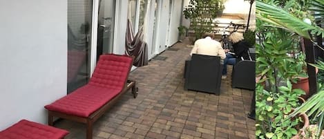 Een terras met rode loungestoelen, een hangstoel en een zithoek met een tafel.