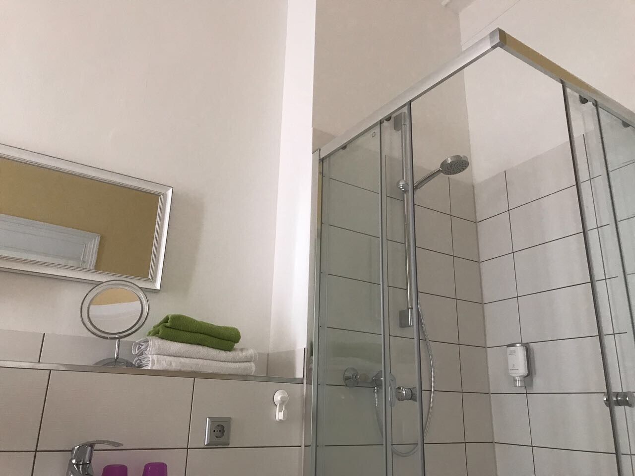 Ein modernes Badezimmer mit Duschkabine aus Glas, einem Spiegel und einem Handtuchhalter mit gefalteten Handtüchern.