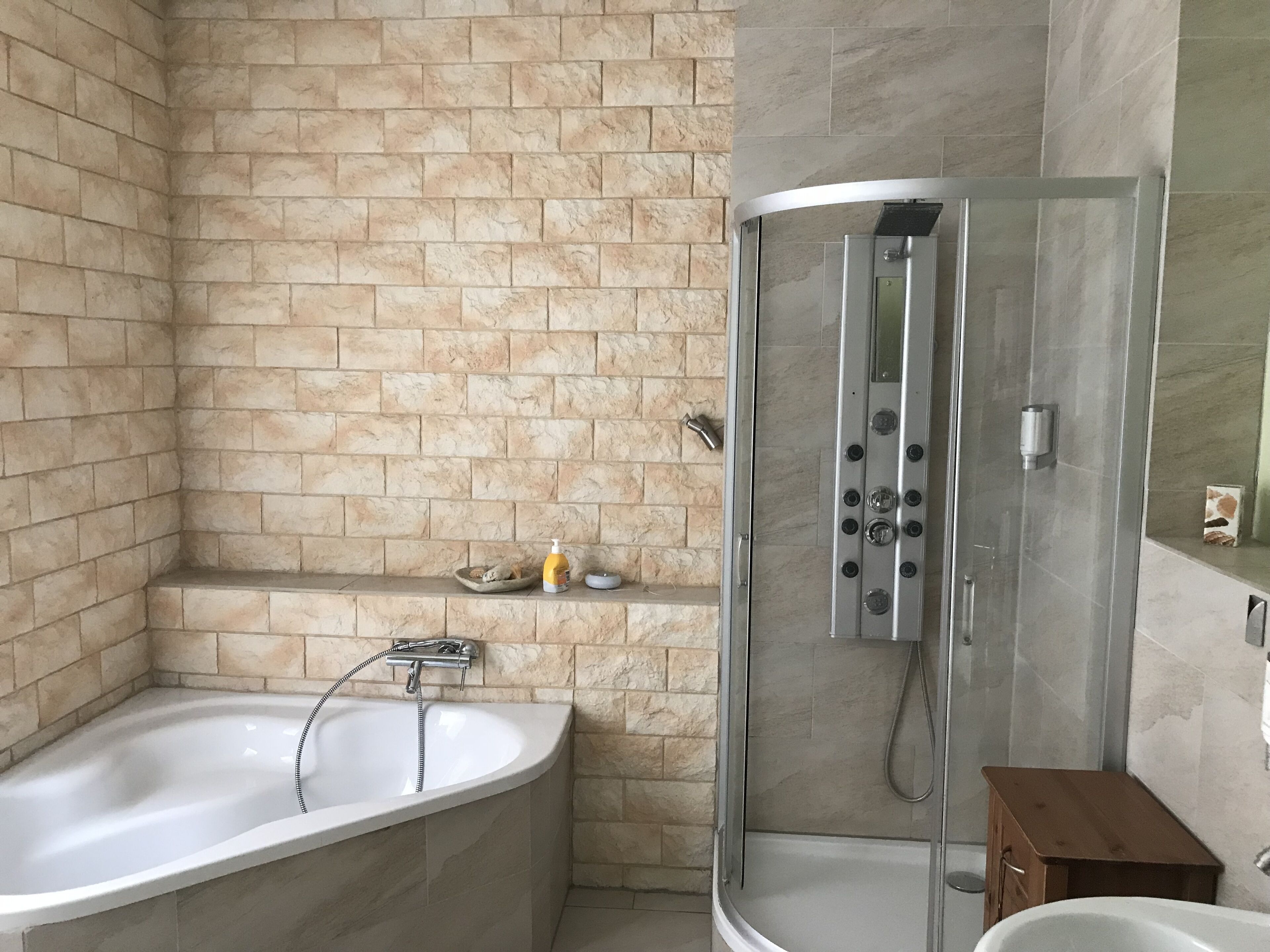 A modern bathroom with a freestanding bathtub, a glass-enclosed shower, and a small wooden cabinet.