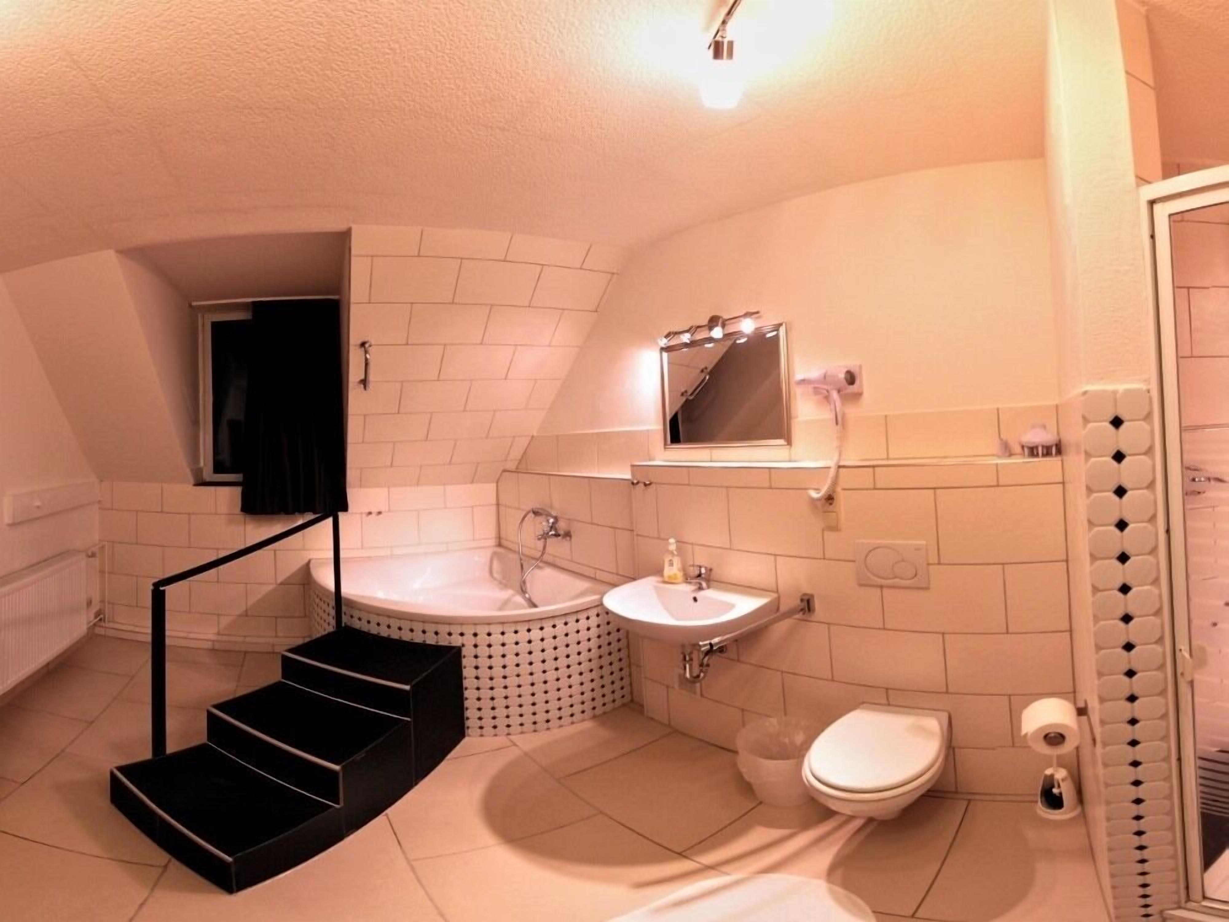 A compact bathroom with a bathtub, sink, toilet, and a mirror above the sink.