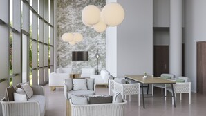 Una sala de estar moderna con mobiliario de mimbre, una mesa de comedor y un ventanal con luz natural.