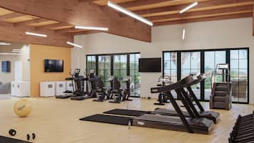 Un gimnasio con cintas de correr, elípticas y pesas libres.