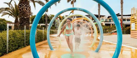 A water play area with blue arches and palm trees in the background.