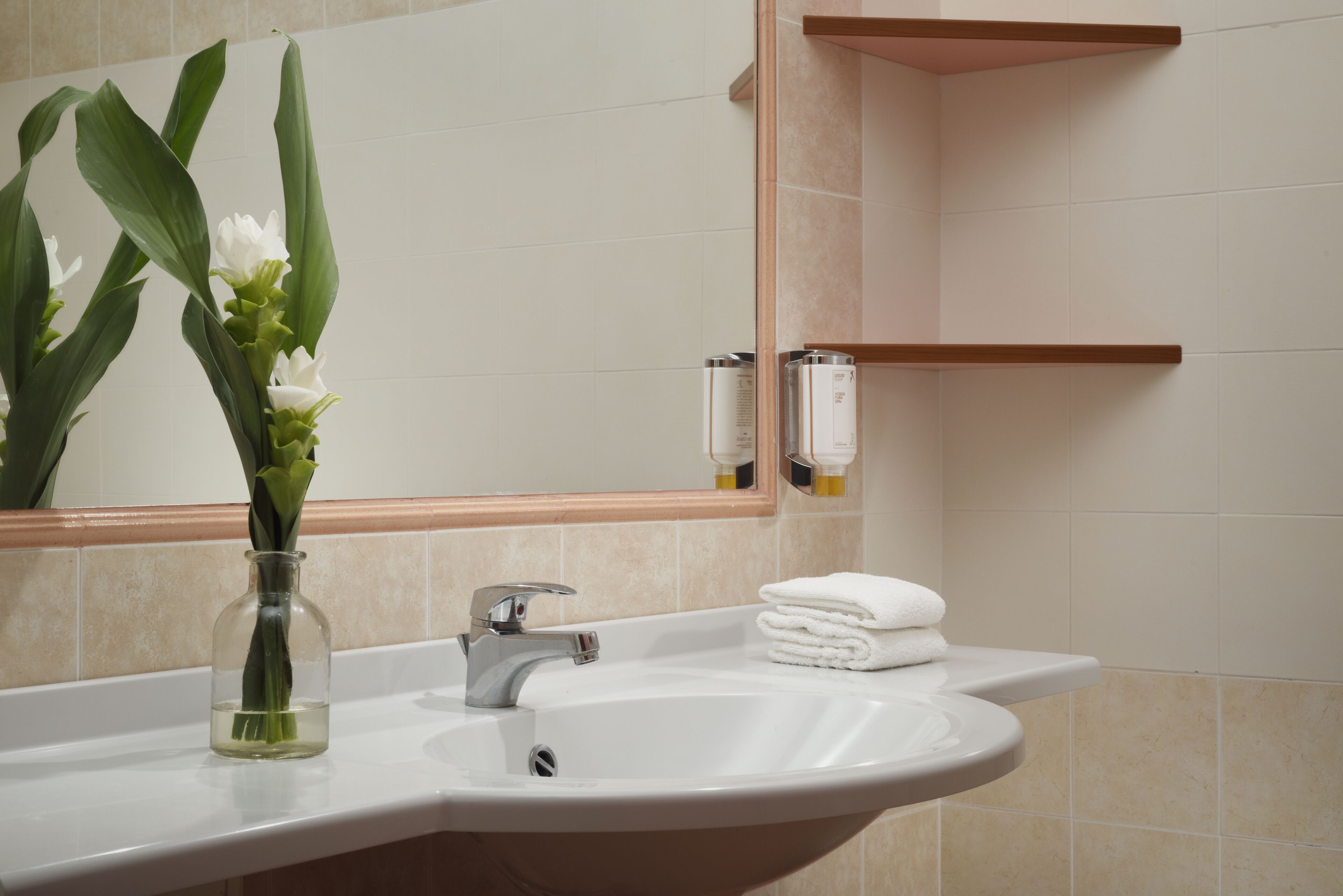 A bathroom with a sink, mirror, and towel rack.