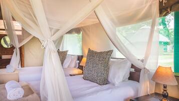 A bed with white linens, a canopy, and a patterned pillow.