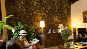 A cozy lobby with a stone wall, leather seating, and a wooden reception desk. - Garahotel (Garachico)