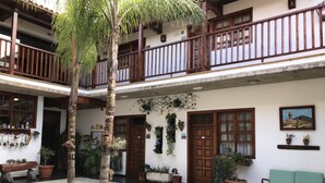 A courtyard with a wooden bench, potted plants, and a palm tree. - Garahotel (Garachico)