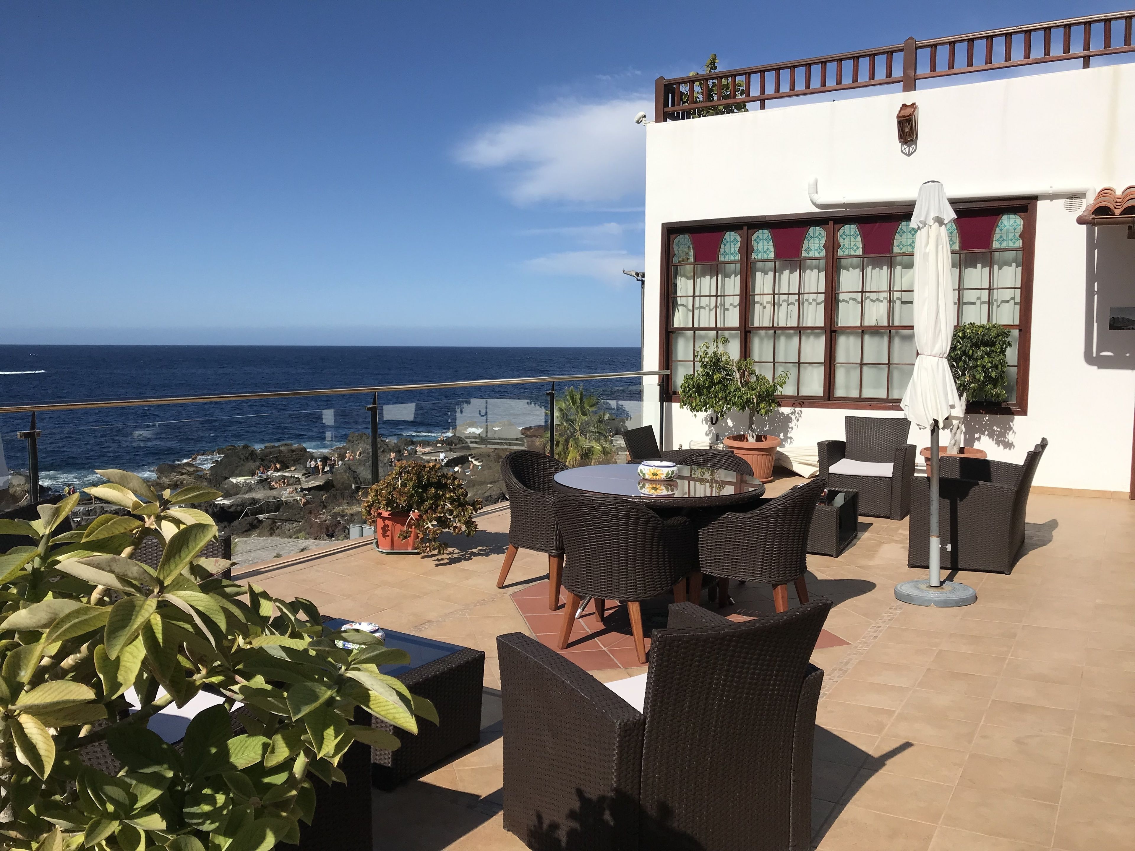 A terrace with wicker furniture, a potted plant, and a view of the ocean.