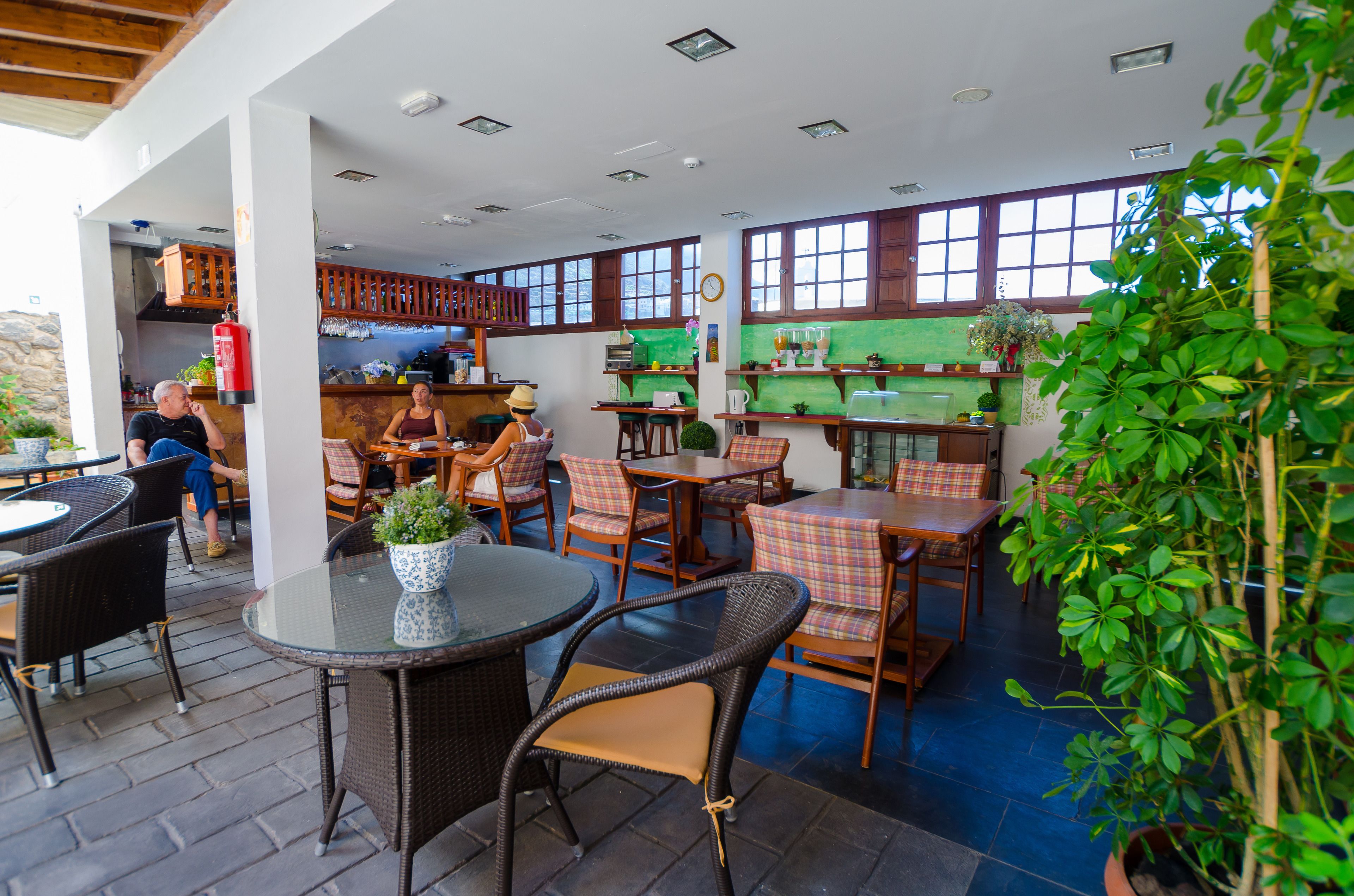 An outdoor patio area with wicker furniture, a fire extinguisher, and a view of the kitchen area.