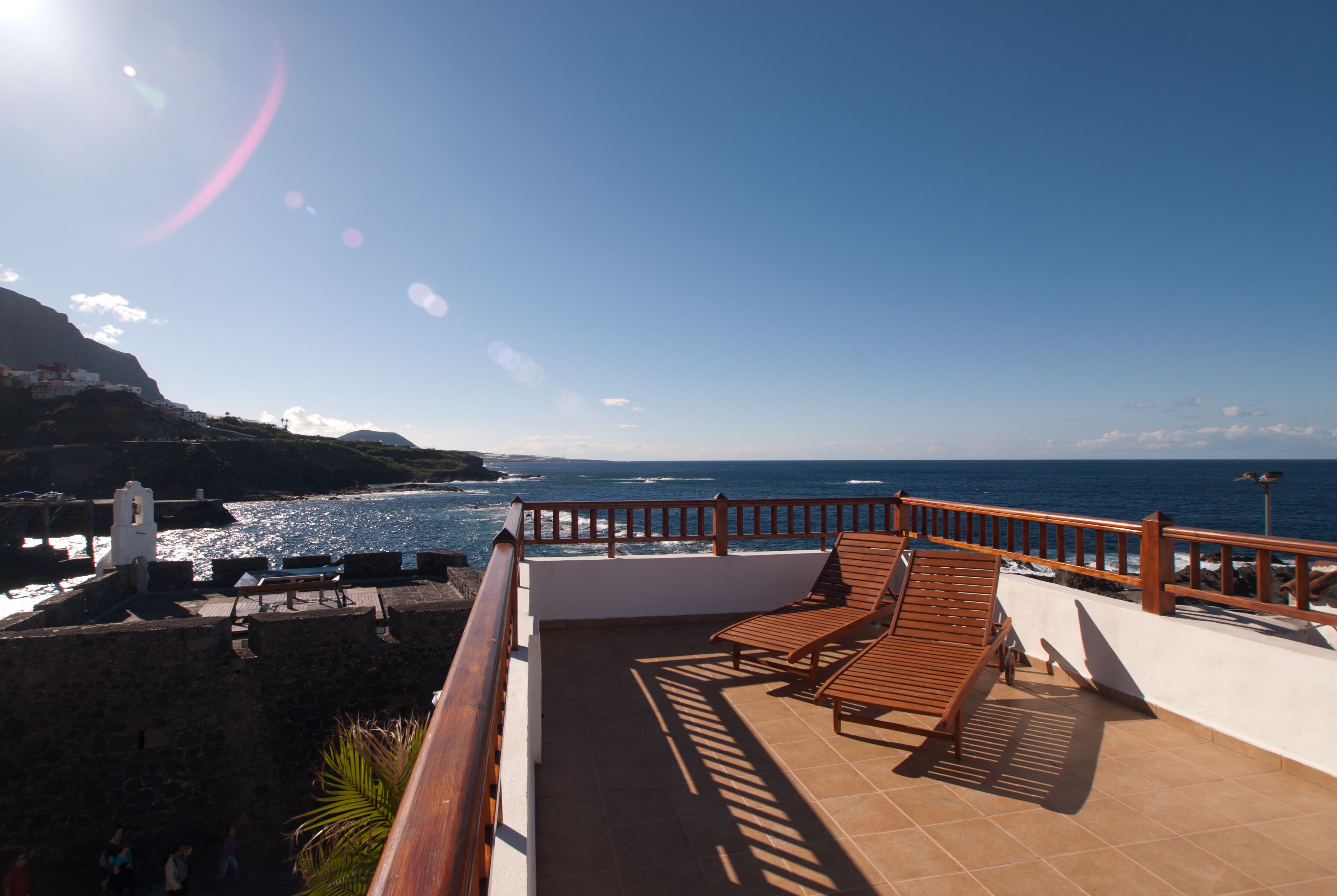 A terrace with wooden chairs and a view of the ocean.