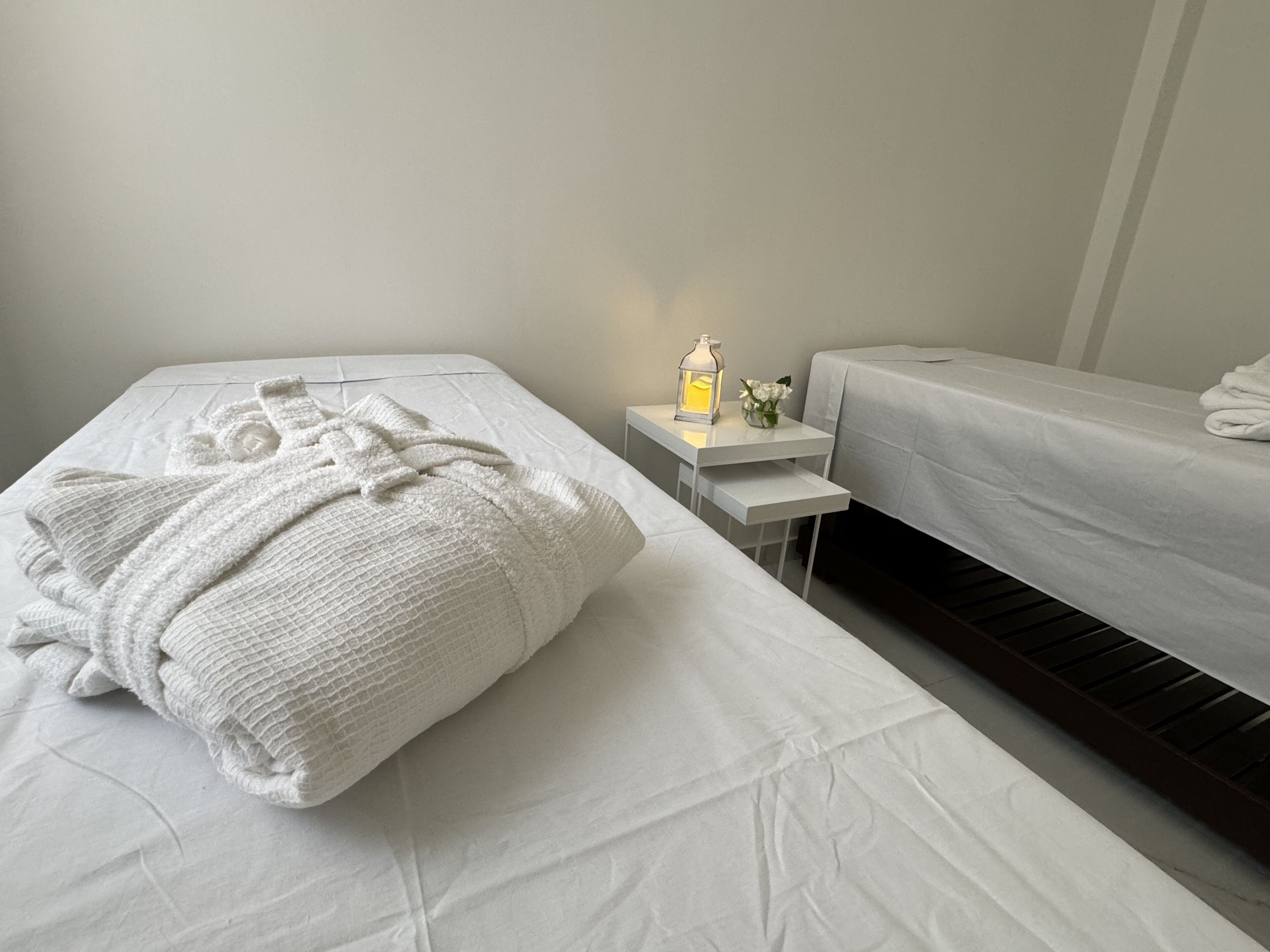 Una habitación de hotel con dos camas, una mesita de noche con lámpara y una pequeña mesa con un jarrón de flores.