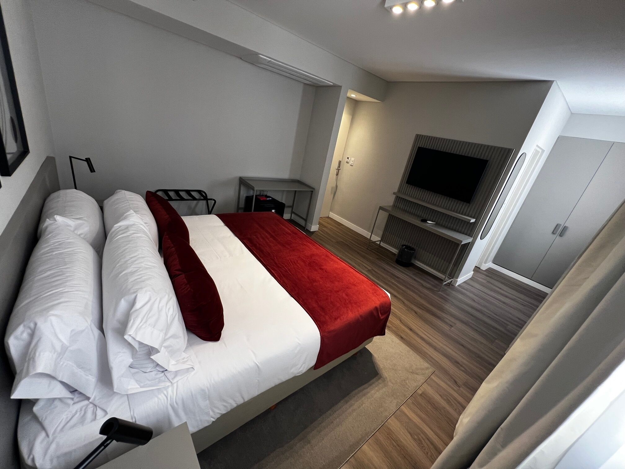 Ein modernes Hotelzimmer mit einem großen Bett, einem Fernseher und einem Kleiderschrank.