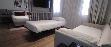 A hotel room with two beds, a TV mounted on the wall, and a small table.