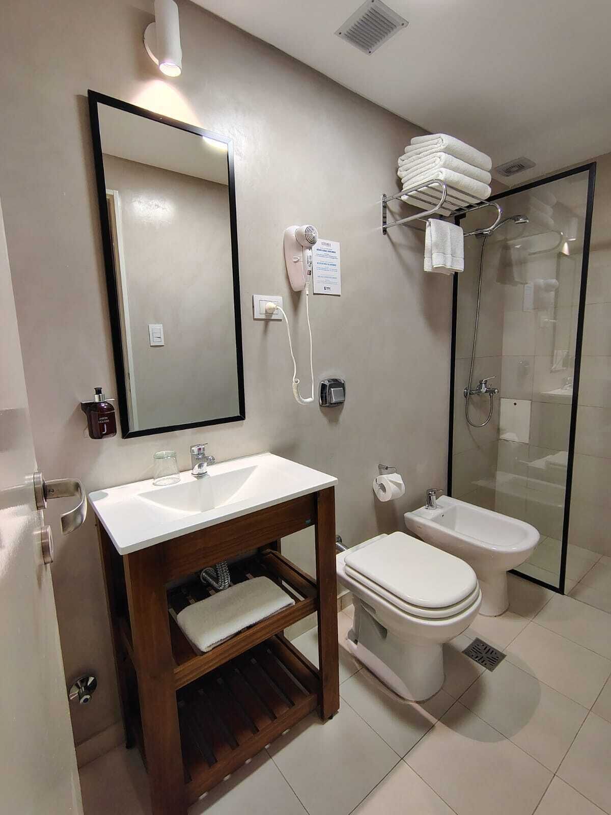 Une salle de bain moderne équipée d’un lavabo, d’un miroir, de toilettes, d’un bidet et d’une douche à parois de verre.