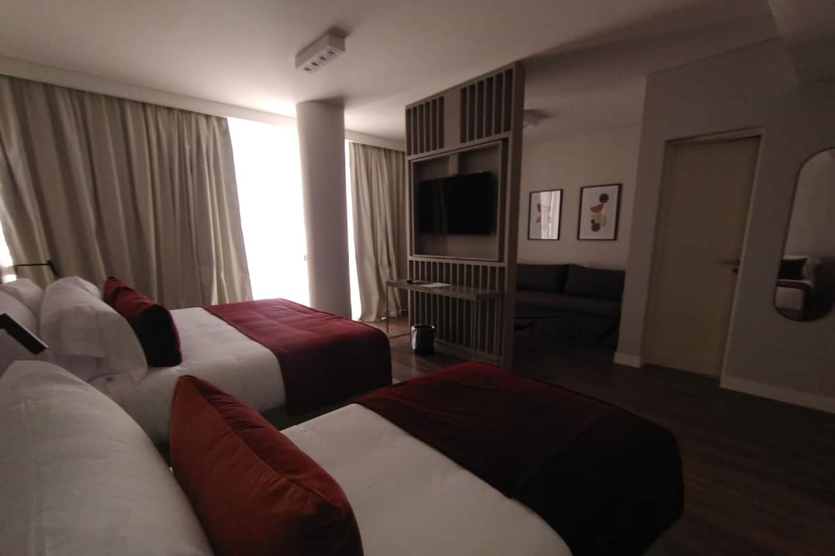 Ett hotellrum med två sängar, en TV, en soffa och en matplats.