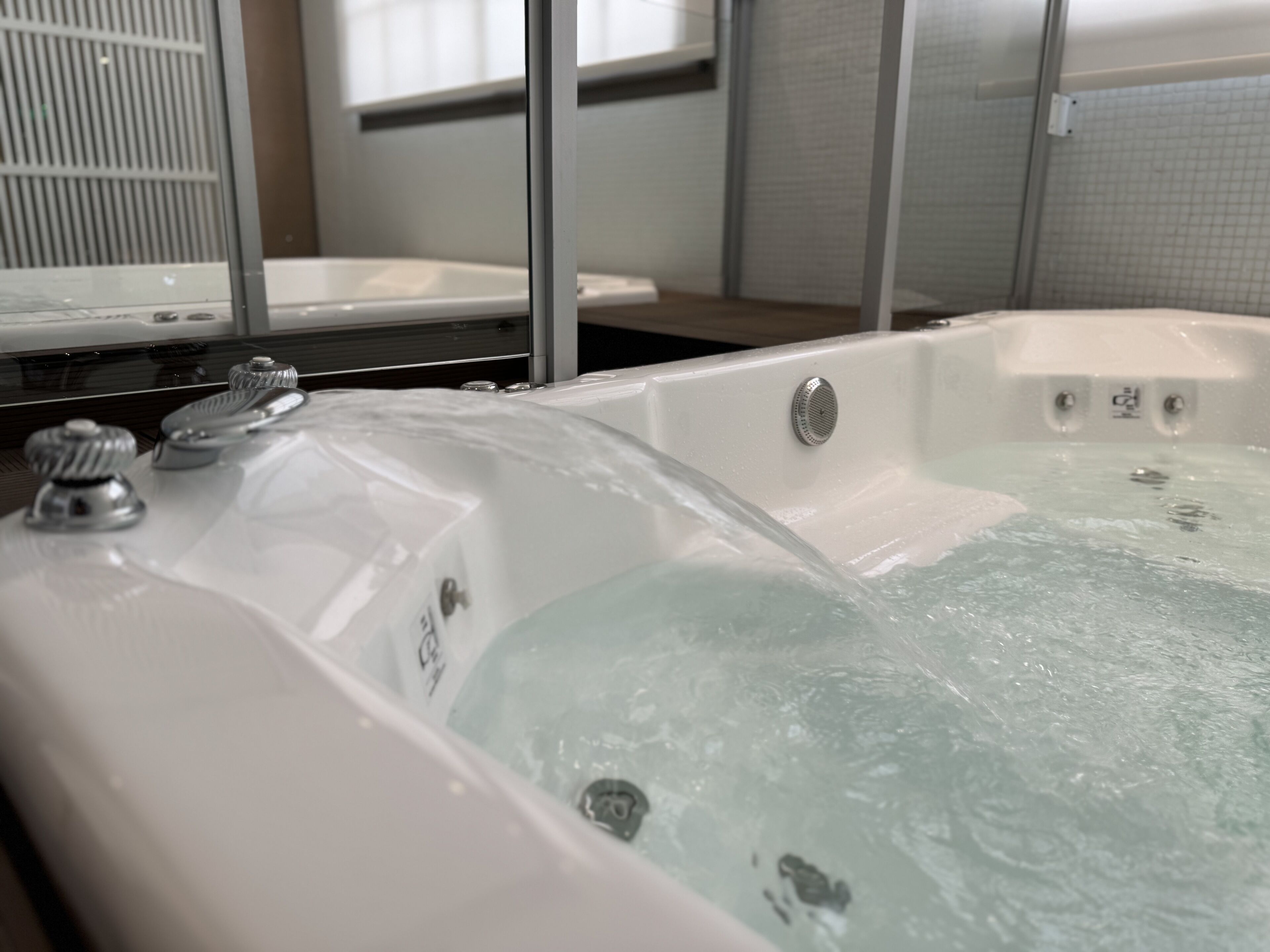 Un baño moderno con una bañera grande, un espejo y una zona de ducha.