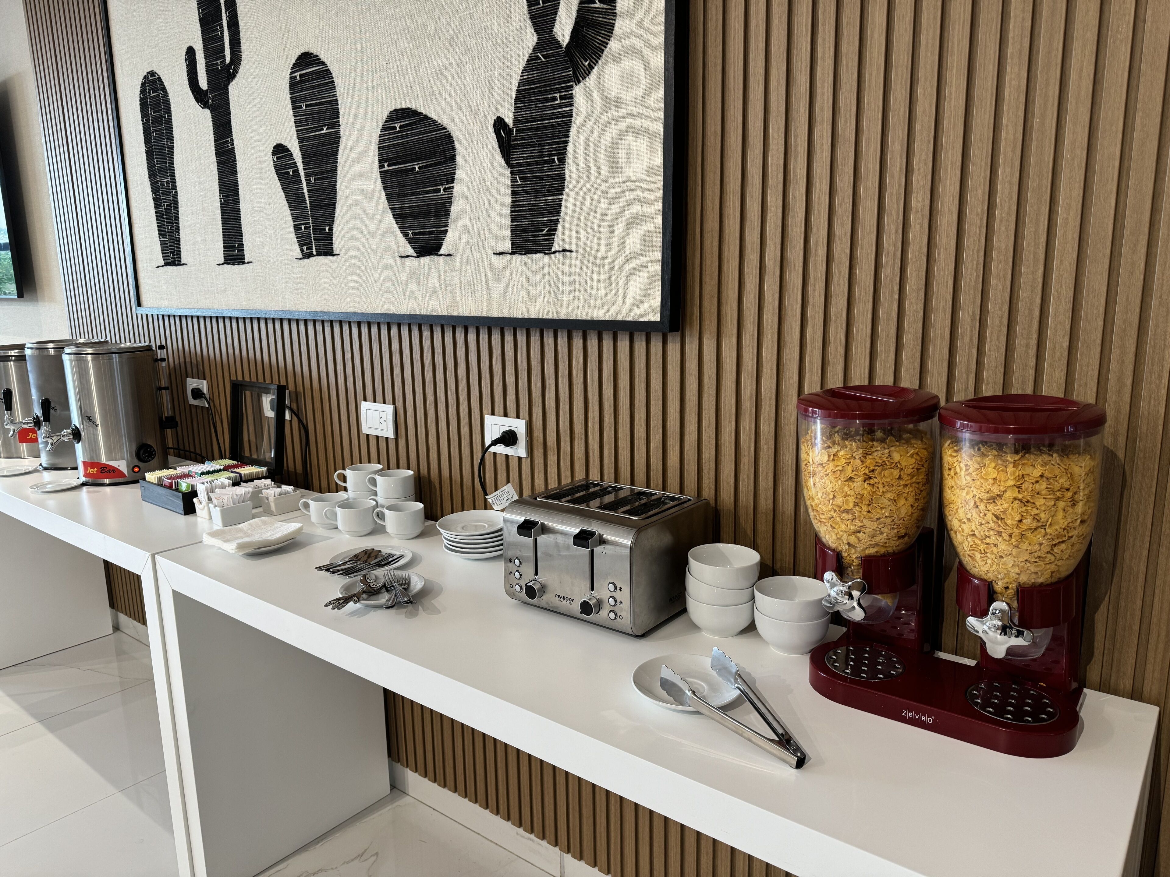 A breakfast bar with coffee dispensers, a toaster, and cereal dispensers.