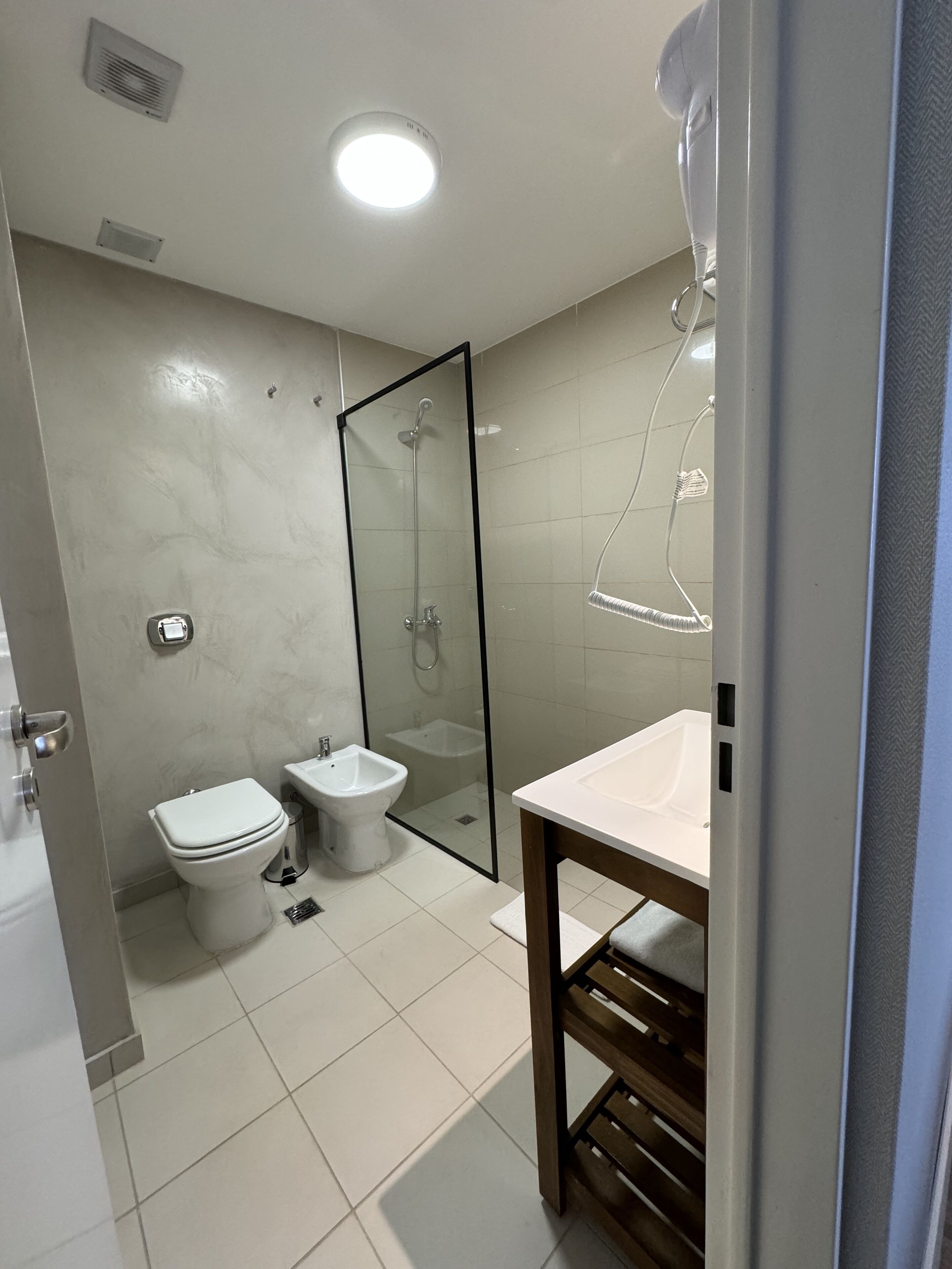 A modern bathroom with a toilet, bidet, and glass-enclosed shower.