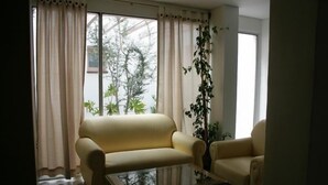 A living room with a beige sofa, a glass coffee table, and a potted plant. - RJ Hotel del Sol (Mendoza)