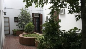 A courtyard with a tiled floor, wooden planters, and a variety of potted plants. - RJ Hotel del Sol (Mendoza)