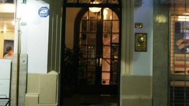 A building entrance with an arched doorway, a sign above the door, and a green sign above the entrance. - RJ Hotel del Sol (Mendoza)